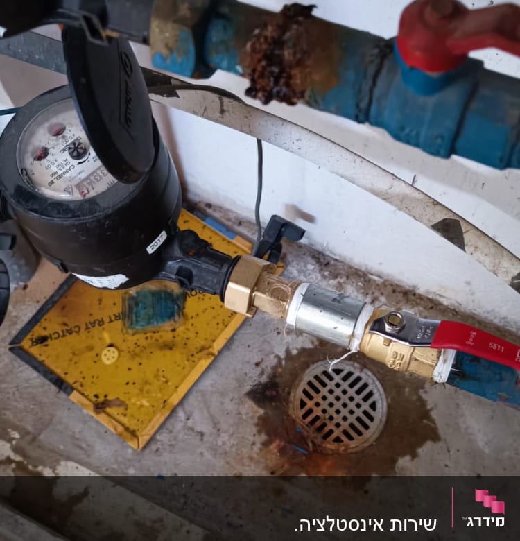 צינור מים עם ברז אדום ומד מים